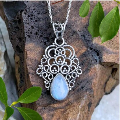 An image of a pendant with a group of sterling silver swirls and circles with a teardrop shaped rainbow moonstone pendant at the bottom.