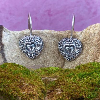 a image of a pair of feminine Sterling Silver Heart Hook Earrings with an antique look of one larger heart with a smaller one in the center of each earrings