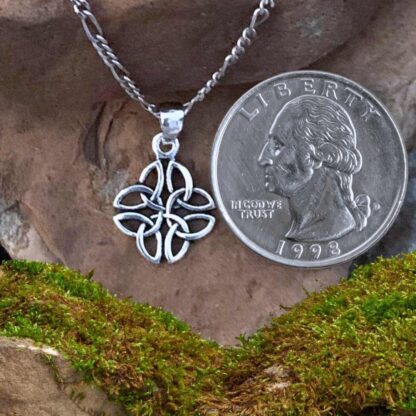 An image of a pendant with four triquetra or trinity celtic knots interwoven in sterling silver. The pendant has a total drop of .813 inches by a width of .50 inches. The pendant is next to a quarter for perspective