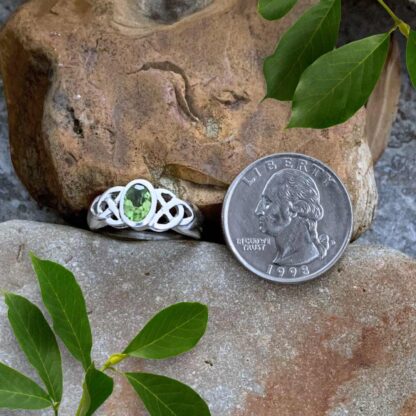 An image of a Peridot & Sterling Silver Celtic Knot Ring next to a quarter