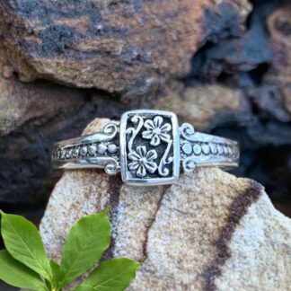 an image of a sterling silver ring with a rectangle shaped frame and two flowers in the frame.