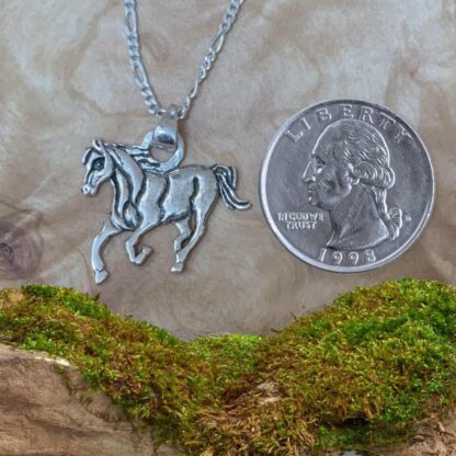 an image of a Sterling Silver Horse Pendant showing one eye as it runs towards you next to a quarter