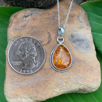 an image of a Teardrop Amber and Sterling Silver Pendant next to a quarter