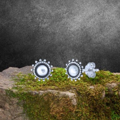 an image of a pair of Sterling Silver Bali Style Stud Earrings with a plain round center surrounded by a silver beaded frame and then a circle of little beads almost like petals on a flower