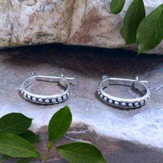 an image of a pair of Sterling Silver Dotted Click Hoop Earrings that are .59 x .55 inches. They are a round shape and have little dots all around the outside against an oxidized background