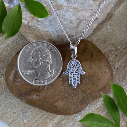 an image of a Dainty Sterling Silver Hamsa Pendant next to a quarter