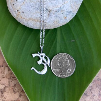 an image of an Om Sterling Silver Pendant next to a quarter