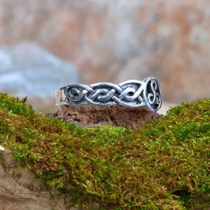 an image of a side view of a sterling silver ring with a Celtic Triskele symbol in a circle in the center and a Celtic knot design on each side