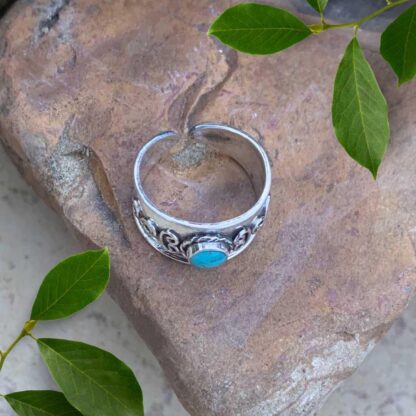 an image of overhead view of an image of a sterling silver Bali Toe Ring with a round turquoise gemstone. Face height is 8.2 mm