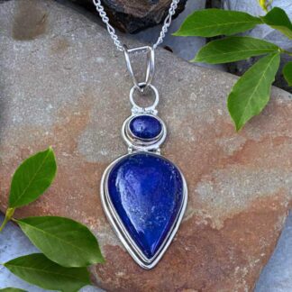 an image of a teardrop shaped lapis lazuli pendant with a smaller oval lapis lazuli stone above it, set in sterling silver. The pendant has a total drop of 2.5 inches and a width of .75 inches