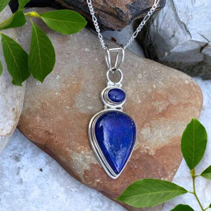 an image of a teardrop shaped lapis lazuli pendant with a smaller oval lapis lazuli stone above it, set in sterling silver. The pendant has a total drop of 2.5 inches and a width of .75 inches