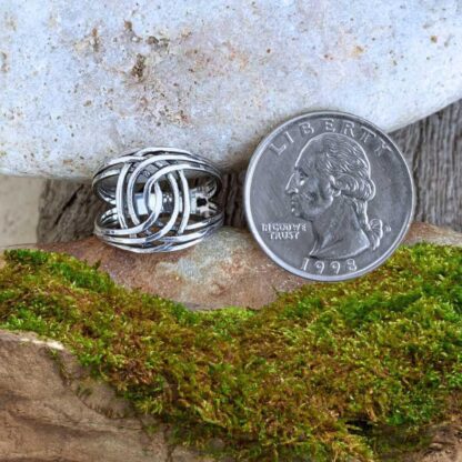 an image of a side view of a an image of a sterling silver double twisted knot ring next to a quarter