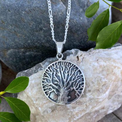 an image of a round sterling silver pendant with oxidation and a dramatic tree.