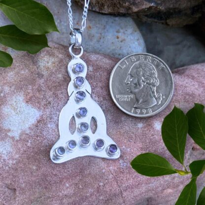 an image of a sterling silver silhouette figure in lotus post with faceted amethyst gemstones in a line down the center and across the bottom with ten amethysts total