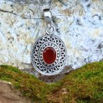 an image of an ornate sterling silver oval pendant with a faceted oval carnelian gemstone in the center