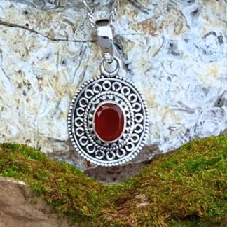 an image of an ornate sterling silver oval pendant with a faceted oval carnelian gemstone in the center