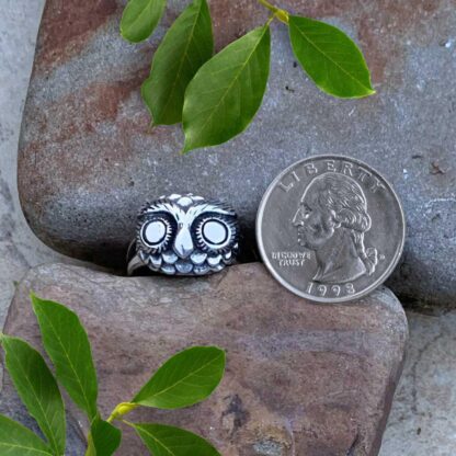 an image of a sterling silver ring of an owl head next to a quarter