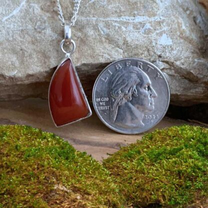 an image of a unique geometric shaped carnelian pendant set in sterling silver with a 1.29 inch drop and next to a quarter