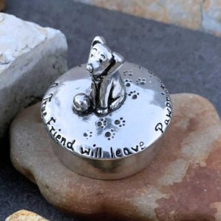 an image of an approximately 2 inch diameter round box with a cute dog on top and paw prints as well as the words "A true friend will leave paw prints in your heart". When you lift the lid there is another little pewter dog that you can take out.