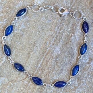 an image of a sterling silver bracelet made of nine linked marquise shaped lapis lazuli gemstones. The bracelet is seven inches long but can be adjusted a little bit larger