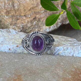 an image of an Oval Amethyst Cabochon and Sterling Silver Ring with a spiral design on each side.