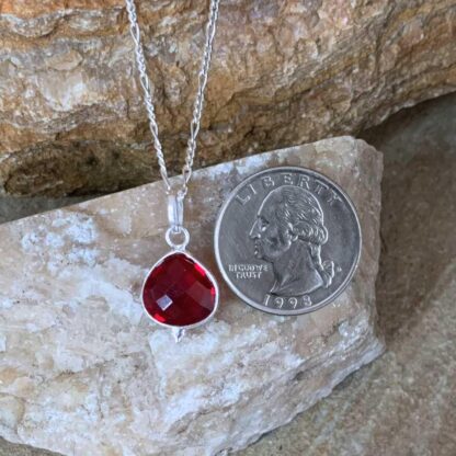 an image of a Petite Faceted Garnet and Sterling Silver Pendant next to a quarter