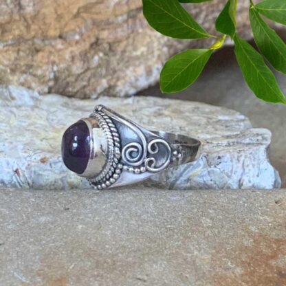 an image of side view of an Oval Amethyst Cabochon and Sterling Silver Ring with a spiral design on each side.