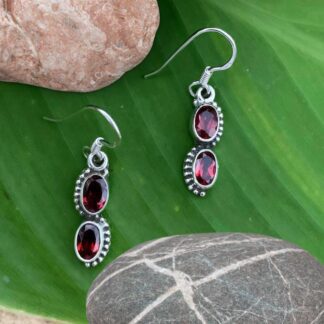 an image of a pair of dangle earrings with two oval faceted garnet gemstones and set in sterling silver