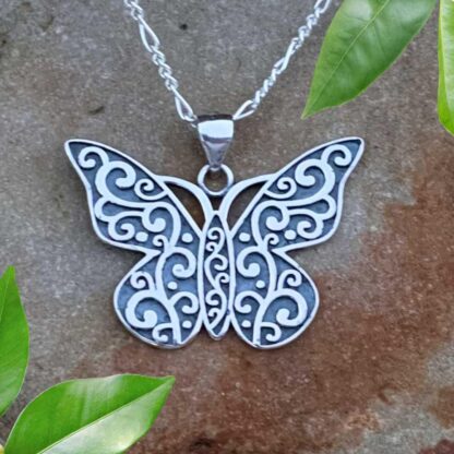 an image of a sterling silver butterfly pendant with oxidation and a swirling pattern all over. The pendant has a .866 total drop