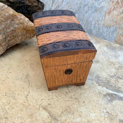 an image of a side view of a Handcrafted Wooden Locking Treasure Chest Made in Poland with a golden color wood and trimmed in a dark brown with swirl patterns. The chest is 5-1/8 in. x 3-1/8 in. x 3 inches