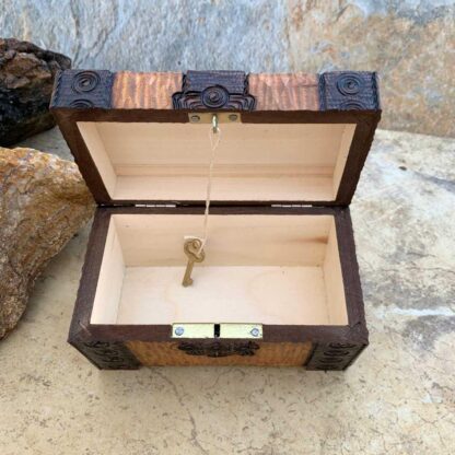 an image of the inside of a Handcrafted Wooden Locking Treasure Chest Made in Poland with a golden color wood and trimmed in a dark brown with swirl patterns. The chest is 5-1/8 in. x 3-1/8 in. x 3 inches