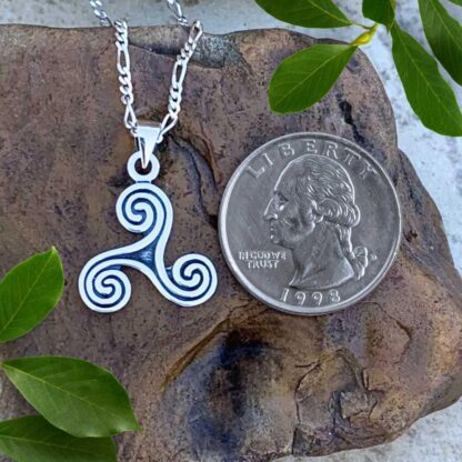 an image of a Sterling Silver Oxidized Celtic Triskelion Pendant next to a quarter with face height of .748 inches