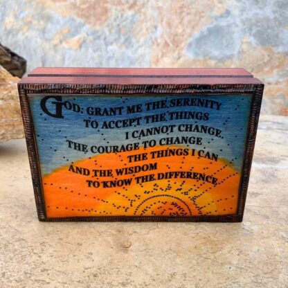 an image of a blue and yellow sky and sun background box with the Serenity Prayer carved on the front. Dimensions are 5 in. x 3-5/8 in. x 1 and a half inches