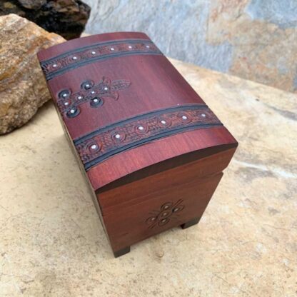 an image of a Pirate Trunk style Keepsake Box handcrafted of wood in a dark burgundy color with black trim. Made in Poland. Dimensions are 5.50 x 3.50 x 3.50 inches. This is a side view