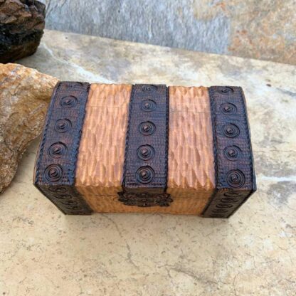 an image of an overhead view of a Handcrafted Wooden Locking Treasure Chest Made in Poland with a golden color wood and trimmed in a dark brown with swirl patterns. The chest is 5-1/8 in. x 3-1/8 in. x 3 inches