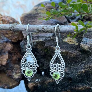 an image of a pair of sterling silver earrings with an upside down open heart and silver beadwork and a small round faceted Peridot gemstone at the bottom.