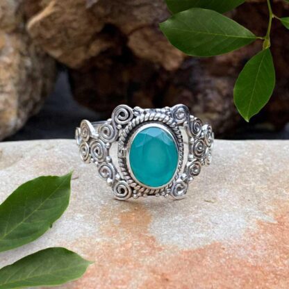 an image of an oval faceted aqua chalcedony gemstone set in sterling silver with a bohemian pattern of multi spirals.