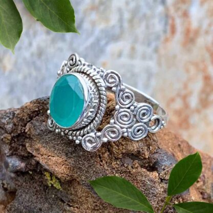 an image of an oval faceted aqua chalcedony gemstone set in sterling silver with a bohemian pattern of multi spirals.