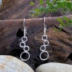 An image of a pair of Contemporary Sterling Circles Dangle Earrings with four open circles staggered and hanging down