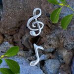 an image of a pair of Sterling Silver Treble Clef & Music Note Stud . One earring is the treble clef and the other is a music note