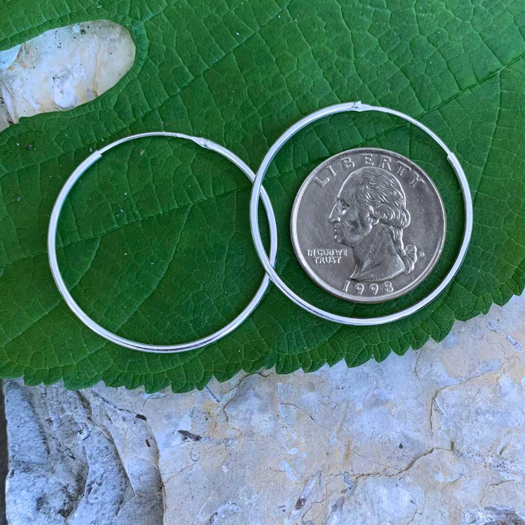 an image of a pair of Sterling Silver 1.4 inch Continuous Hoop Earrings next to a quarter