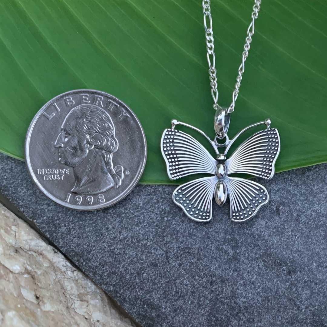 an image of a Vibrant Sterling Silver Butterfly Pendant next to a quarter
