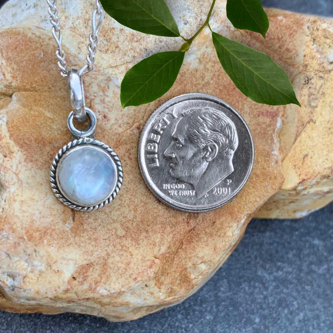 an image of a Petite Round Rainbow Moonstone Sterling Silver Pendant next to a dime