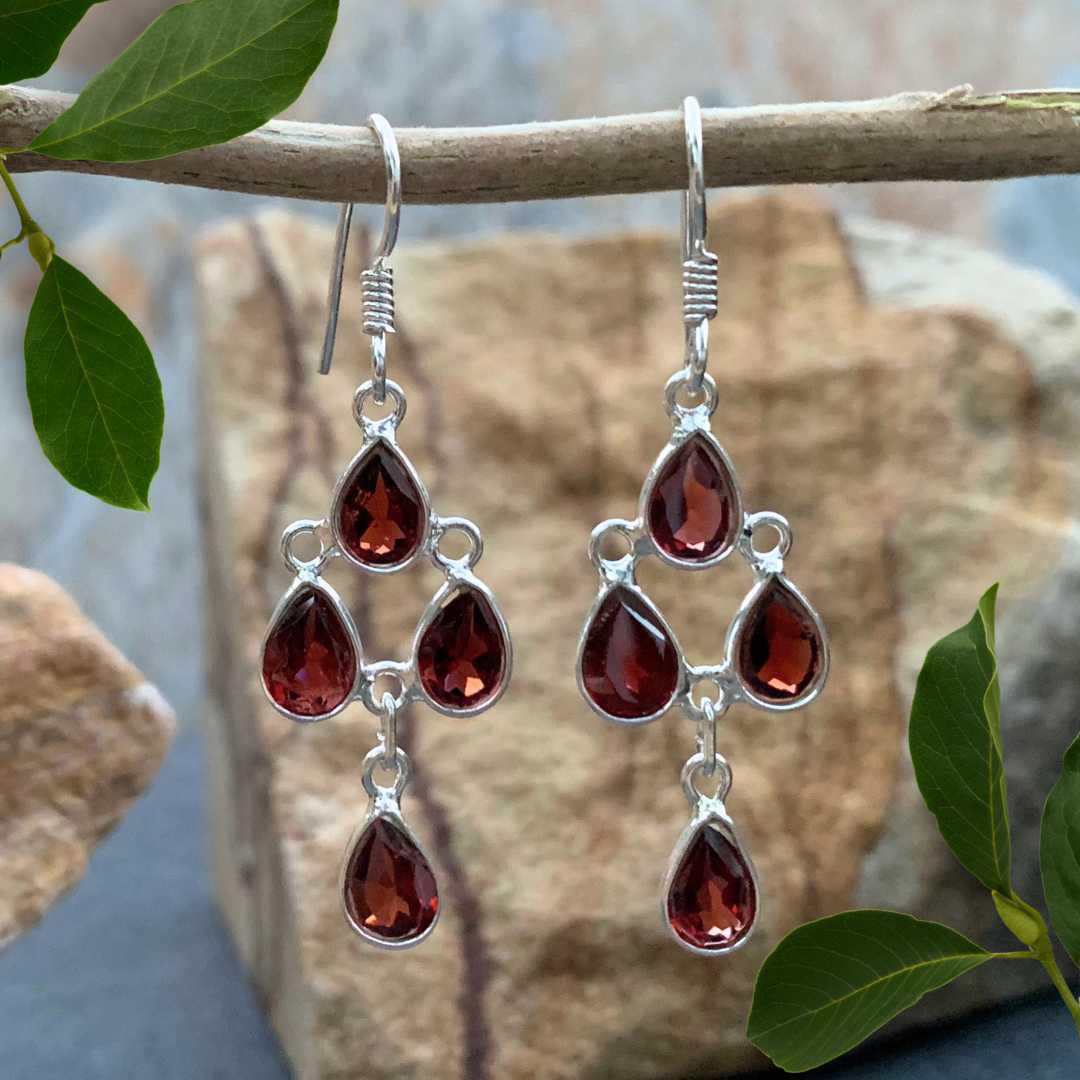 an image of a pair of Garnet and Sterling Silver Chandelier Earrings with four teardrop faceted garnet gemstones dangling down.