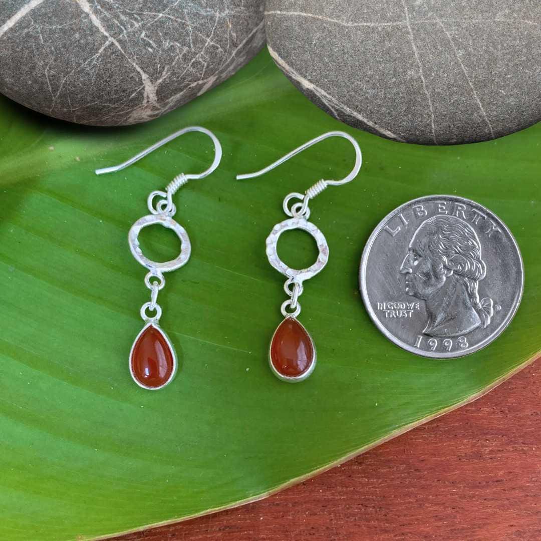 an image of a pair of Hammered Sterling Circle with Carnelian Teardrop Earrings next to a quarter