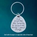 am image of a pewter keychain with one half of the serenity prayer on one side and the other half on the opposite side