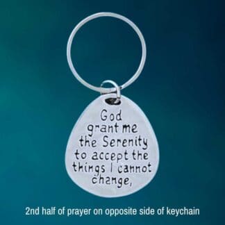 am image of a pewter keychain with one half of the serenity prayer on one side and the other half on the opposite side