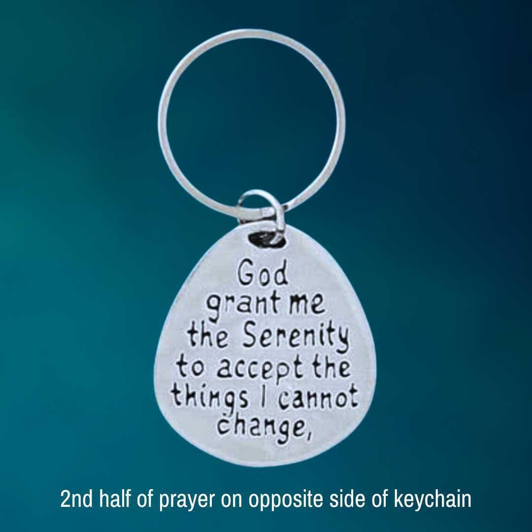 am image of a pewter keychain with one half of the serenity prayer on one side and the other half on the opposite side
