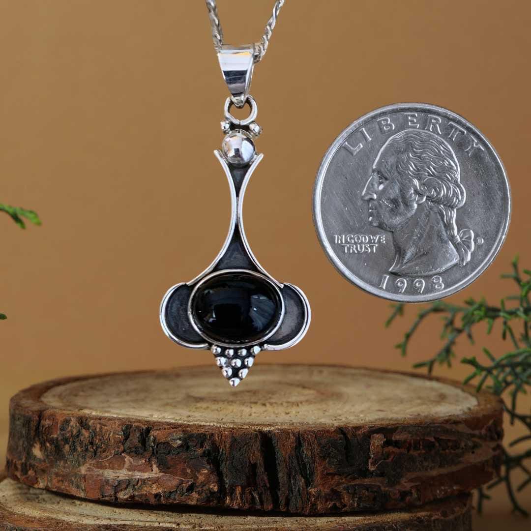 an image of a Oval Black Onyx and Sterling Silver Beaded Pendant next to a quarter
