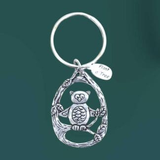 an image of an owl in tree pewter keychain. The owl is in the center of some branches and there is a little pewter tiny charm that says plant a tree